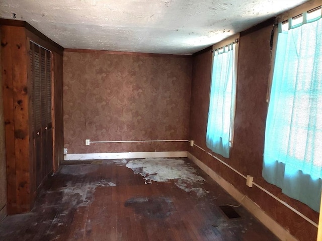 unfurnished room with a textured ceiling, baseboards, and wood-type flooring
