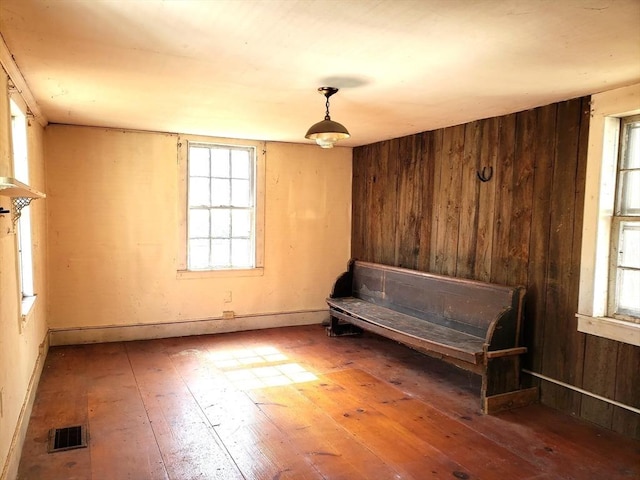 unfurnished room featuring visible vents, wood walls, and hardwood / wood-style flooring