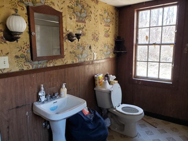 bathroom with wooden walls, wallpapered walls, a wainscoted wall, toilet, and tile patterned floors