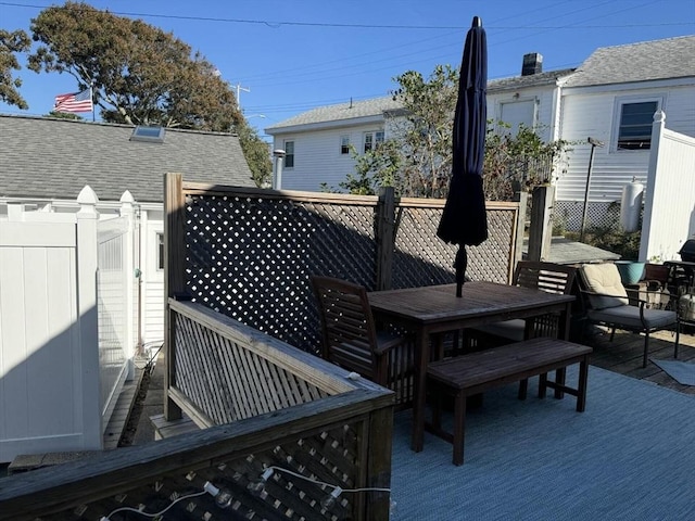 wooden terrace with outdoor dining area and fence