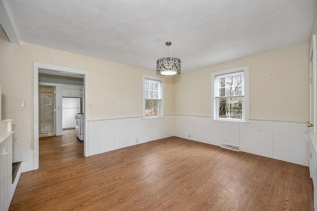 interior space featuring visible vents, a wainscoted wall, and wood finished floors