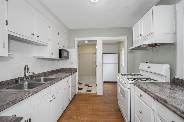 kitchen with white appliances, dark wood-style flooring, a sink, under cabinet range hood, and white cabinetry