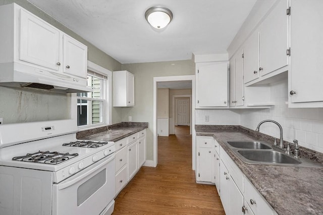 kitchen featuring white cabinets, white gas range, under cabinet range hood, and a sink