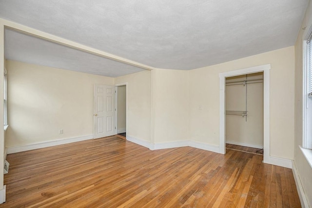 unfurnished bedroom with a closet, baseboards, and hardwood / wood-style floors