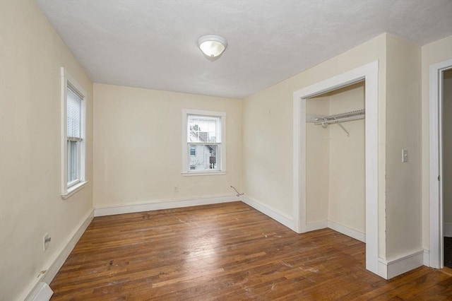 unfurnished bedroom featuring a closet, baseboards, and hardwood / wood-style floors