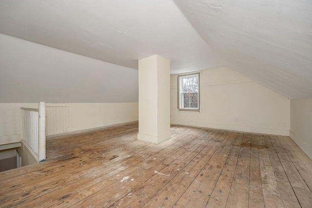 additional living space featuring hardwood / wood-style floors, lofted ceiling, and baseboards