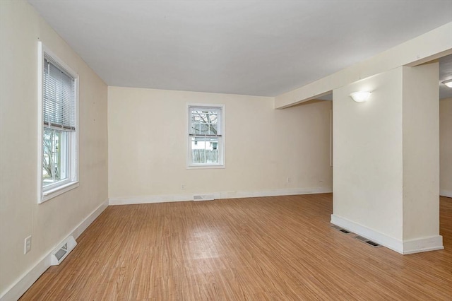 unfurnished room featuring visible vents, light wood-style flooring, and baseboards