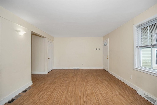 unfurnished room with light wood finished floors, visible vents, and baseboards