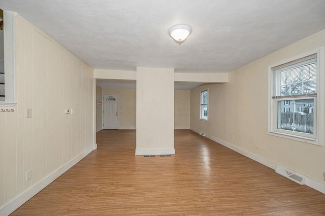 spare room featuring a textured ceiling, baseboards, visible vents, and light wood-type flooring