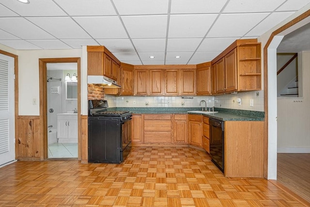 kitchen featuring open shelves, a sink, black appliances, under cabinet range hood, and wainscoting