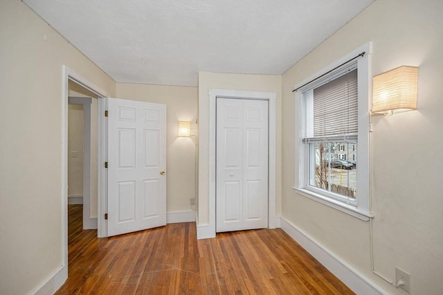 unfurnished bedroom featuring a closet, baseboards, and wood finished floors