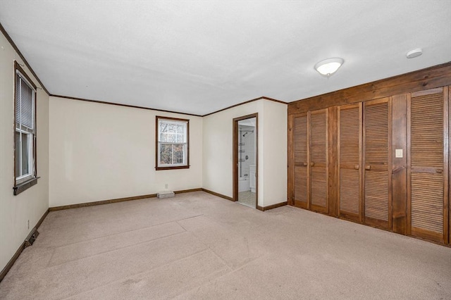 unfurnished bedroom with baseboards, ornamental molding, a textured ceiling, light carpet, and connected bathroom