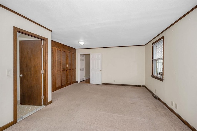 spare room with light carpet, visible vents, crown molding, and baseboards