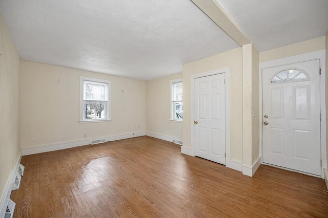 foyer entrance with wood finished floors, visible vents, and baseboards