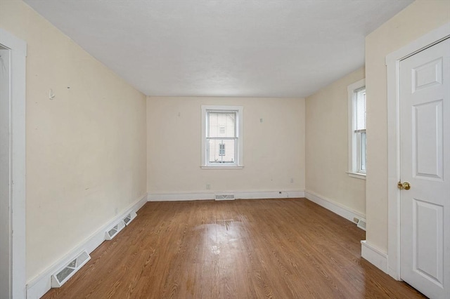 spare room with visible vents, baseboards, and wood finished floors