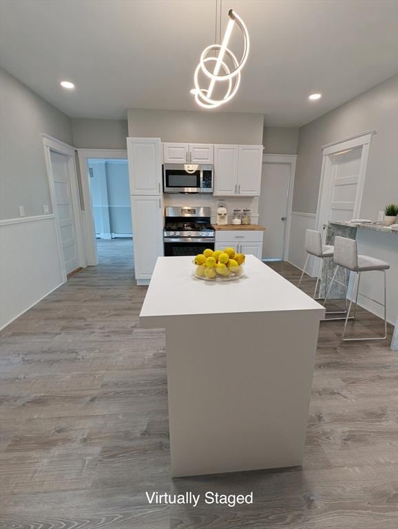 16 Horton St Unit 2, Salem, MA 01970 - kitchen featuring appliances with stainless steel finishes, wood finished floors, white cabinets, a wainscoted wall, and pendant lighting