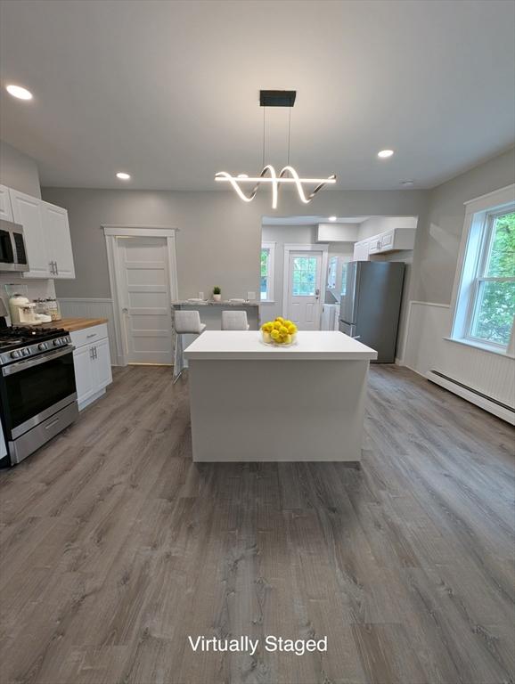16 Horton St Unit 2, Salem, MA 01970 - kitchen with appliances with stainless steel finishes, white cabinetry, wood finished floors, light countertops, and a kitchen island