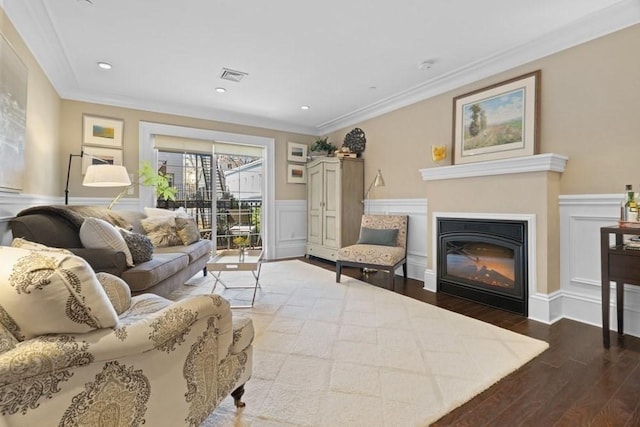living area featuring a glass covered fireplace, wainscoting, wood finished floors, and visible vents