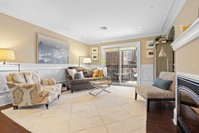 interior space with visible vents, ornamental molding, wood finished floors, and a decorative wall