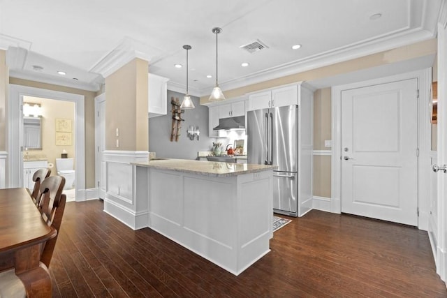 kitchen with freestanding refrigerator, ornamental molding, a peninsula, light stone countertops, and under cabinet range hood