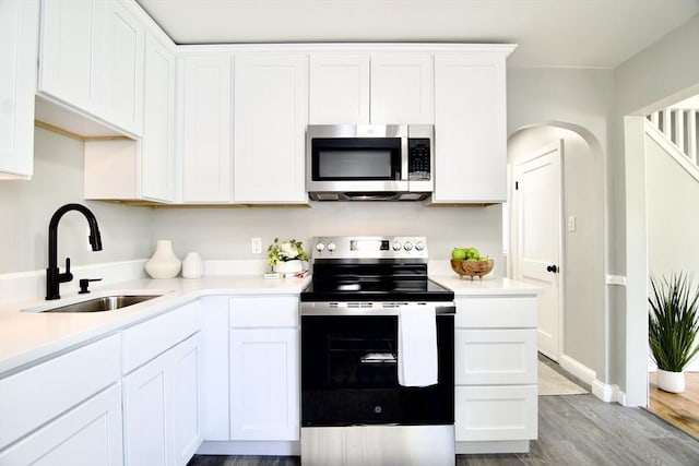 100 Haskin St, Springfield, MA 01109 - kitchen featuring appliances with stainless steel finishes, wood finished floors, light countertops, white cabinetry, and arched walkways