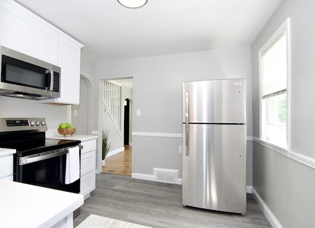 100 Haskin St, Springfield, MA 01109 - kitchen featuring appliances with stainless steel finishes, light countertops, arched walkways, and white cabinetry