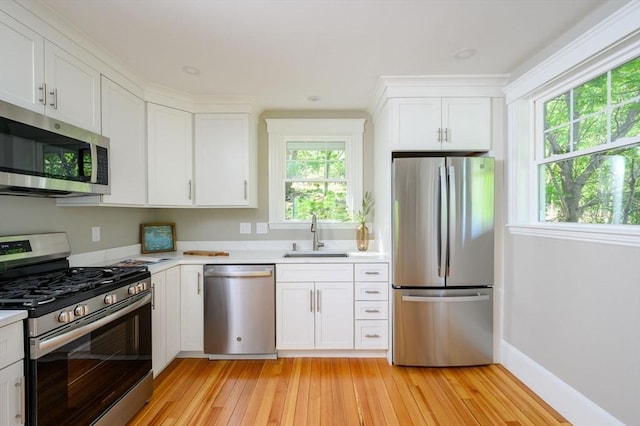 9 School St, Hull, MA 02045 - kitchen featuring appliances with stainless steel finishes, a sink, light countertops, light wood-style floors, and white cabinetry