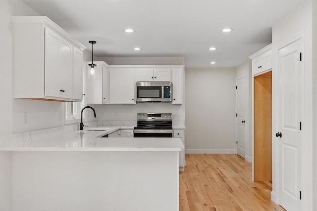 7 S Porter St Unit 7, Haverhill, MA 01835 - kitchen with stainless steel appliances, a peninsula, light wood-type flooring, recessed lighting, and white cabinets