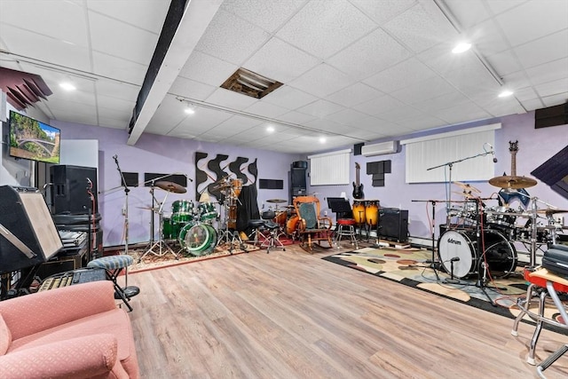 workout area featuring a drop ceiling, wood finished floors, and a wall unit AC