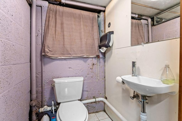 bathroom featuring toilet and concrete block wall