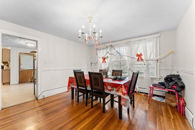 dining space with a notable chandelier, a baseboard heating unit, and wood finished floors