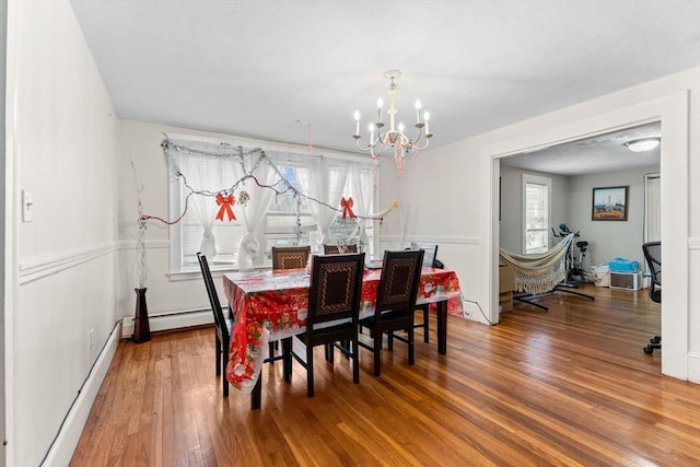 dining area with hardwood / wood-style floors, a notable chandelier, a baseboard heating unit, and a baseboard radiator