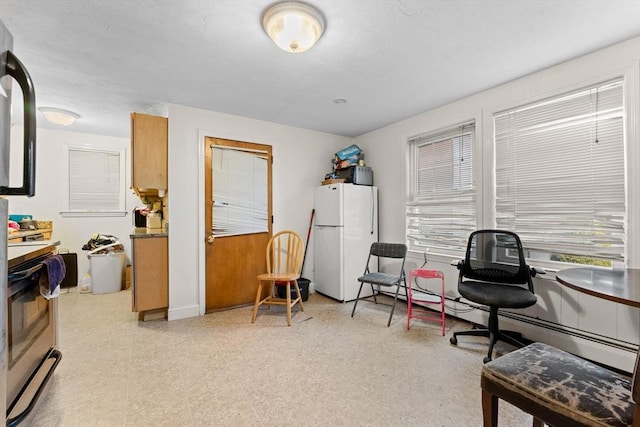 interior space with a healthy amount of sunlight, a baseboard heating unit, and light floors