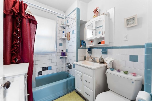 bathroom with vanity, a wainscoted wall, bathing tub / shower combination, tile walls, and toilet