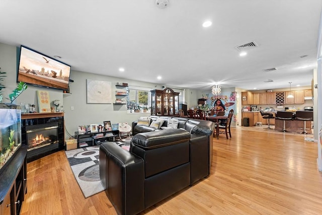 living room with a tiled fireplace, recessed lighting, visible vents, and light wood-type flooring