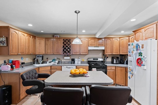 kitchen with a kitchen island, under cabinet range hood, light countertops, recessed lighting, and white appliances