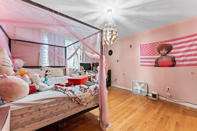 bedroom featuring a chandelier, baseboards, and wood finished floors