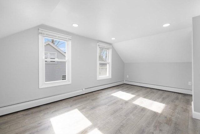 additional living space featuring vaulted ceiling, wood finished floors, recessed lighting, baseboards, and a baseboard radiator