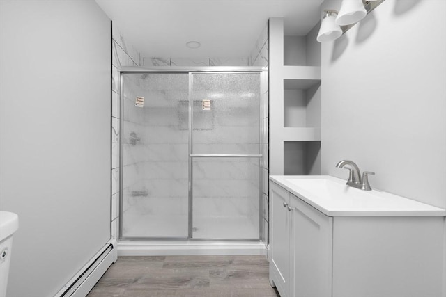 full bathroom featuring a stall shower, wood finished floors, a baseboard heating unit, toilet, and vanity