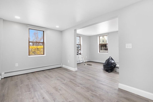 empty room featuring a baseboard radiator, wood finished floors, baseboards, and recessed lighting
