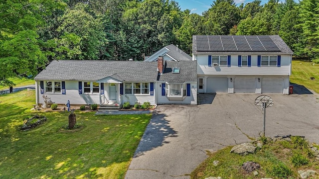 traditional-style house with a garage, driveway, and a front lawn