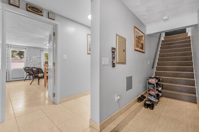 hall with baseboards, stairway, and light tile patterned floors