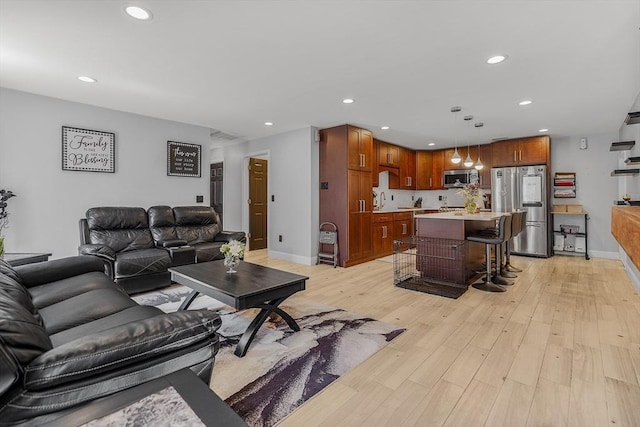 living area featuring baseboards, light wood-type flooring, and recessed lighting