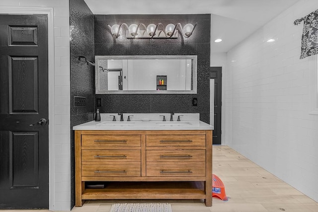 full bathroom with double vanity, wood finished floors, and a sink