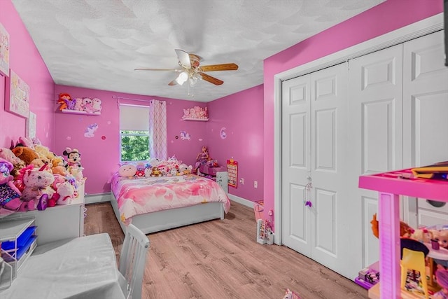 bedroom featuring a textured ceiling, a ceiling fan, wood finished floors, a closet, and a baseboard radiator