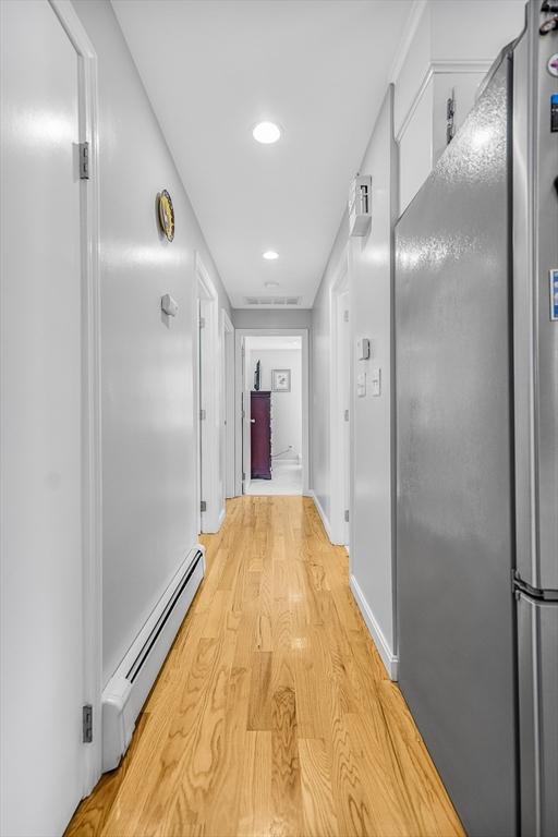 hall with a baseboard heating unit, visible vents, recessed lighting, and light wood-style floors