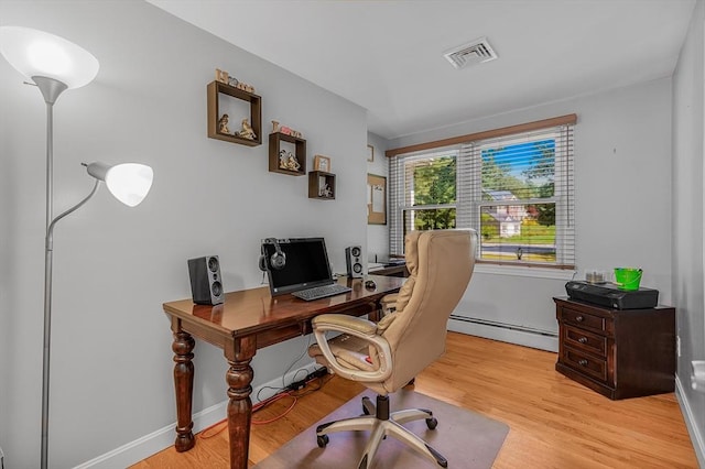 office space with a baseboard radiator, light wood-style floors, and visible vents
