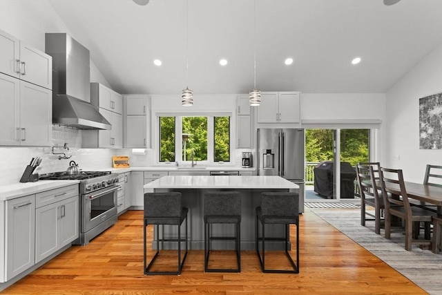 751 Sharps Lot Rd, Swansea, MA 02777 - kitchen featuring stainless steel appliances, wall chimney exhaust hood, vaulted ceiling, healthy amount of natural light, and a kitchen breakfast bar
