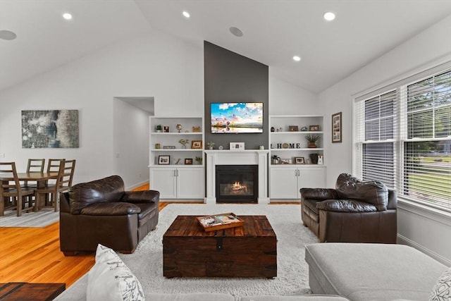 751 Sharps Lot Rd, Swansea, MA 02777 - living area with a glass covered fireplace, high vaulted ceiling, recessed lighting, built in features, and light wood-style flooring