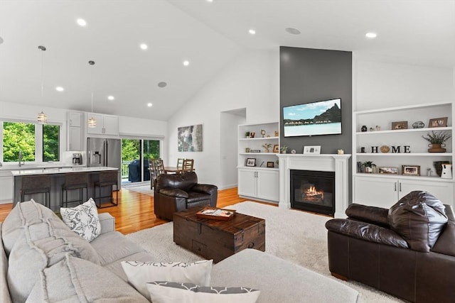 751 Sharps Lot Rd, Swansea, MA 02777 - living room with high vaulted ceiling, a glass covered fireplace, light wood-type flooring, built in features, and recessed lighting